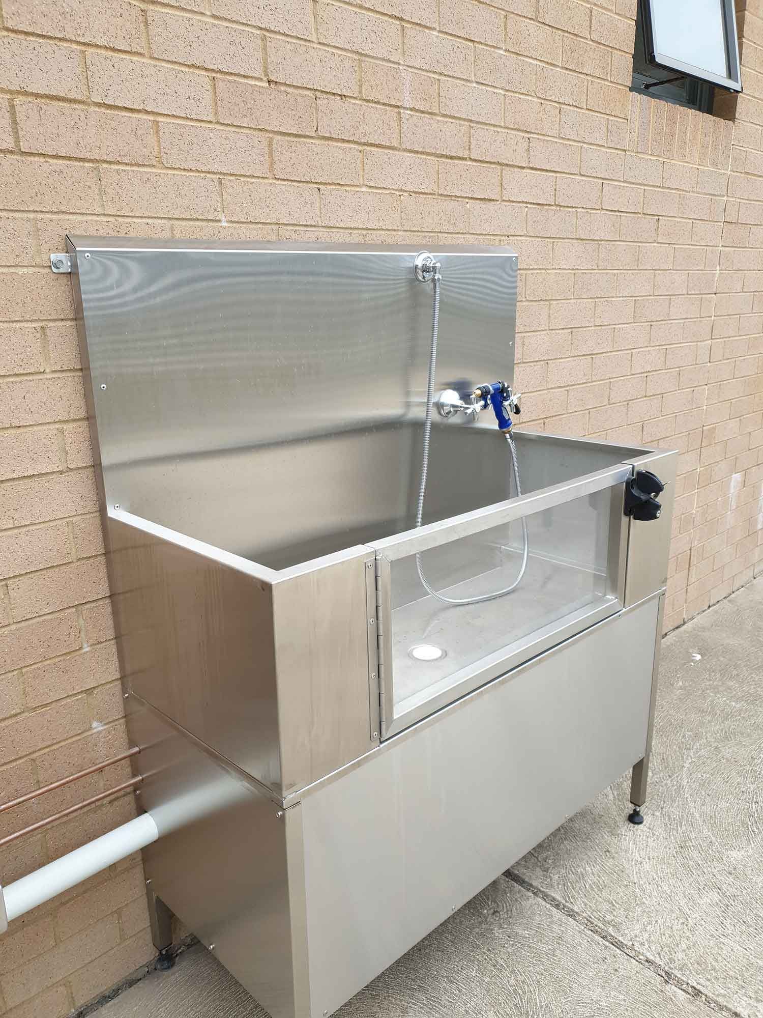 A stainless steel sink is sitting outside of a brick building.