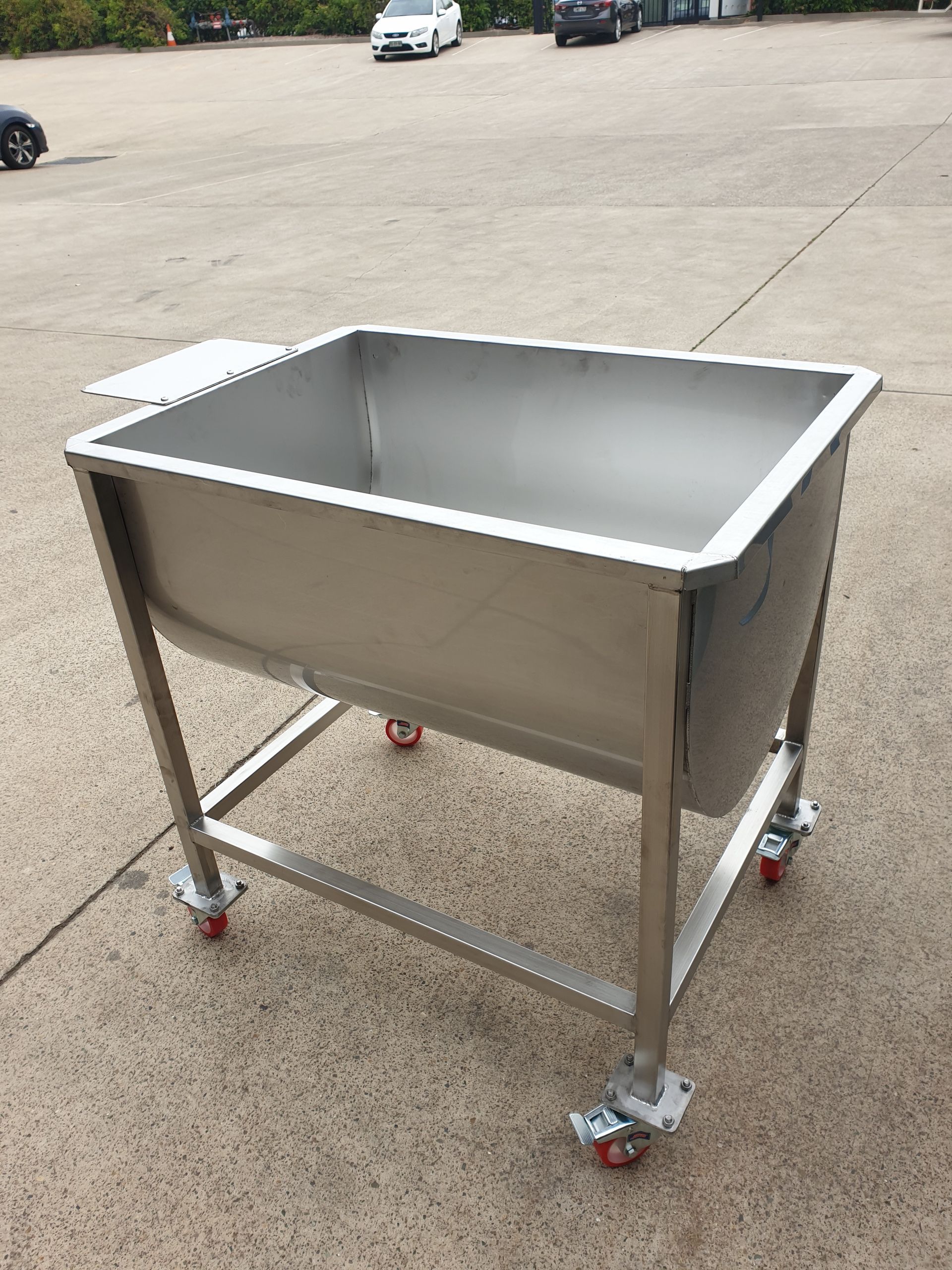 A large stainless steel sink on wheels is sitting on the ground.