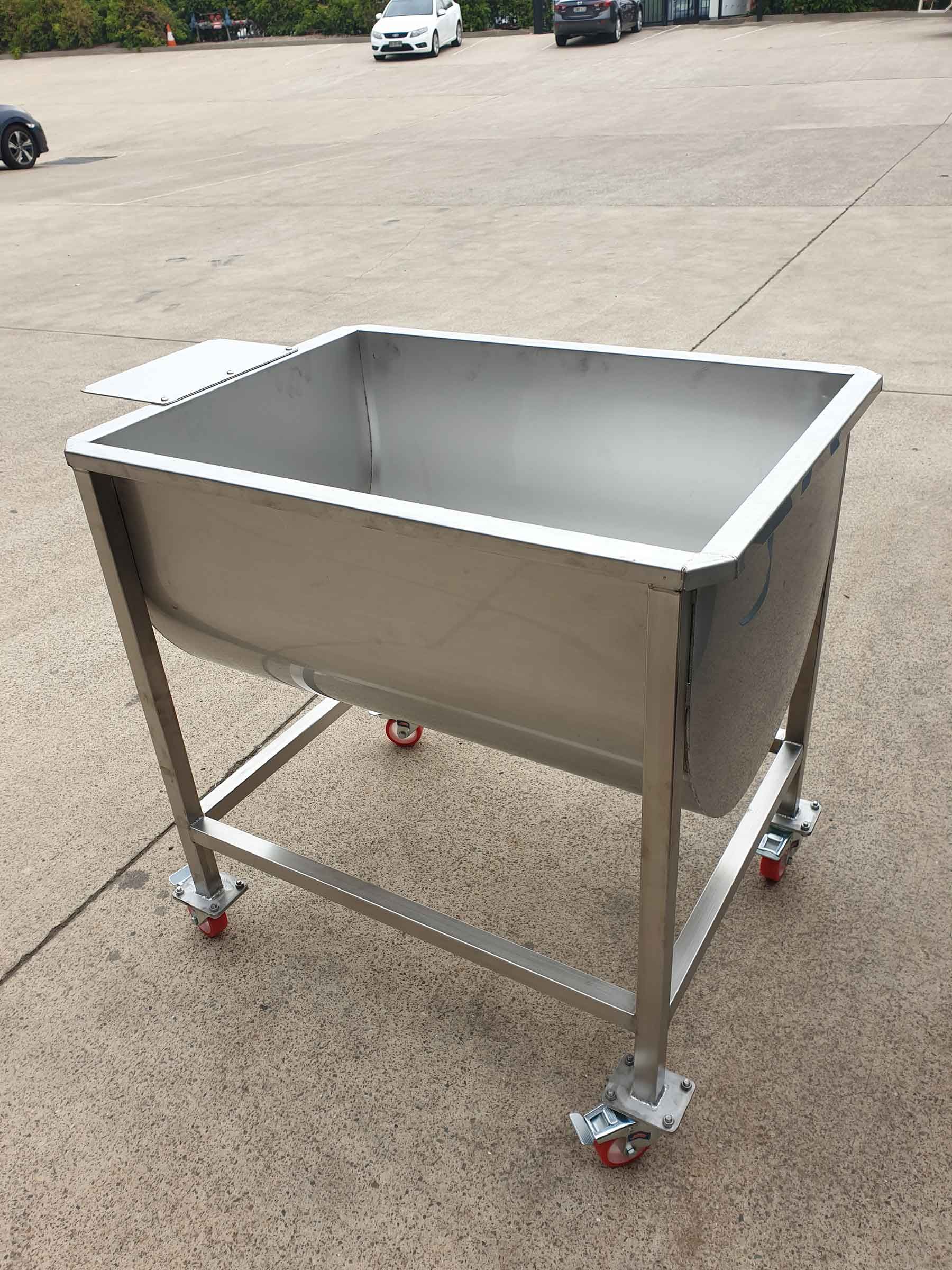 A large stainless steel sink on wheels is sitting on the ground.