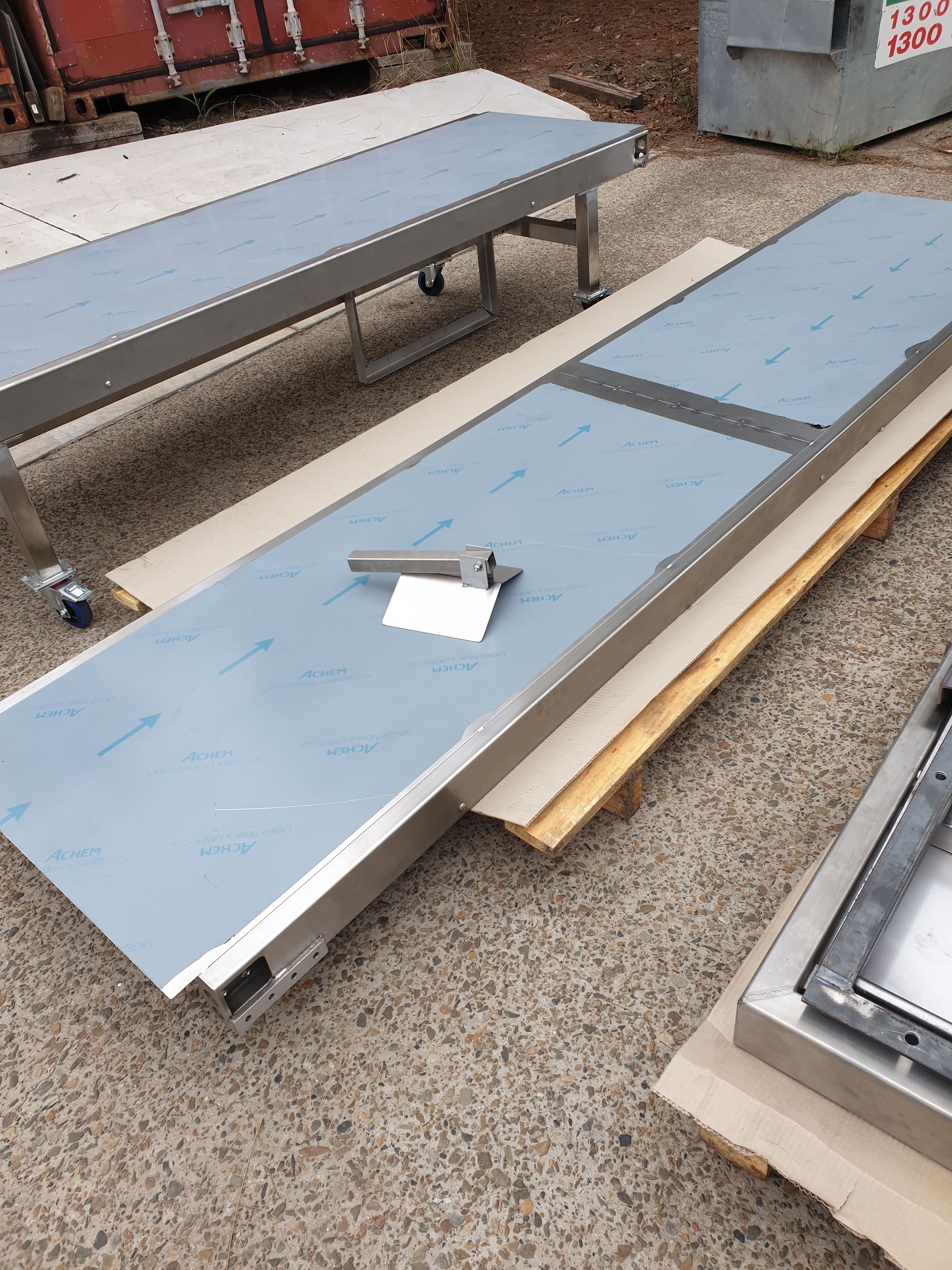 A stainless steel conveyor belt is sitting on top of a wooden pallet.