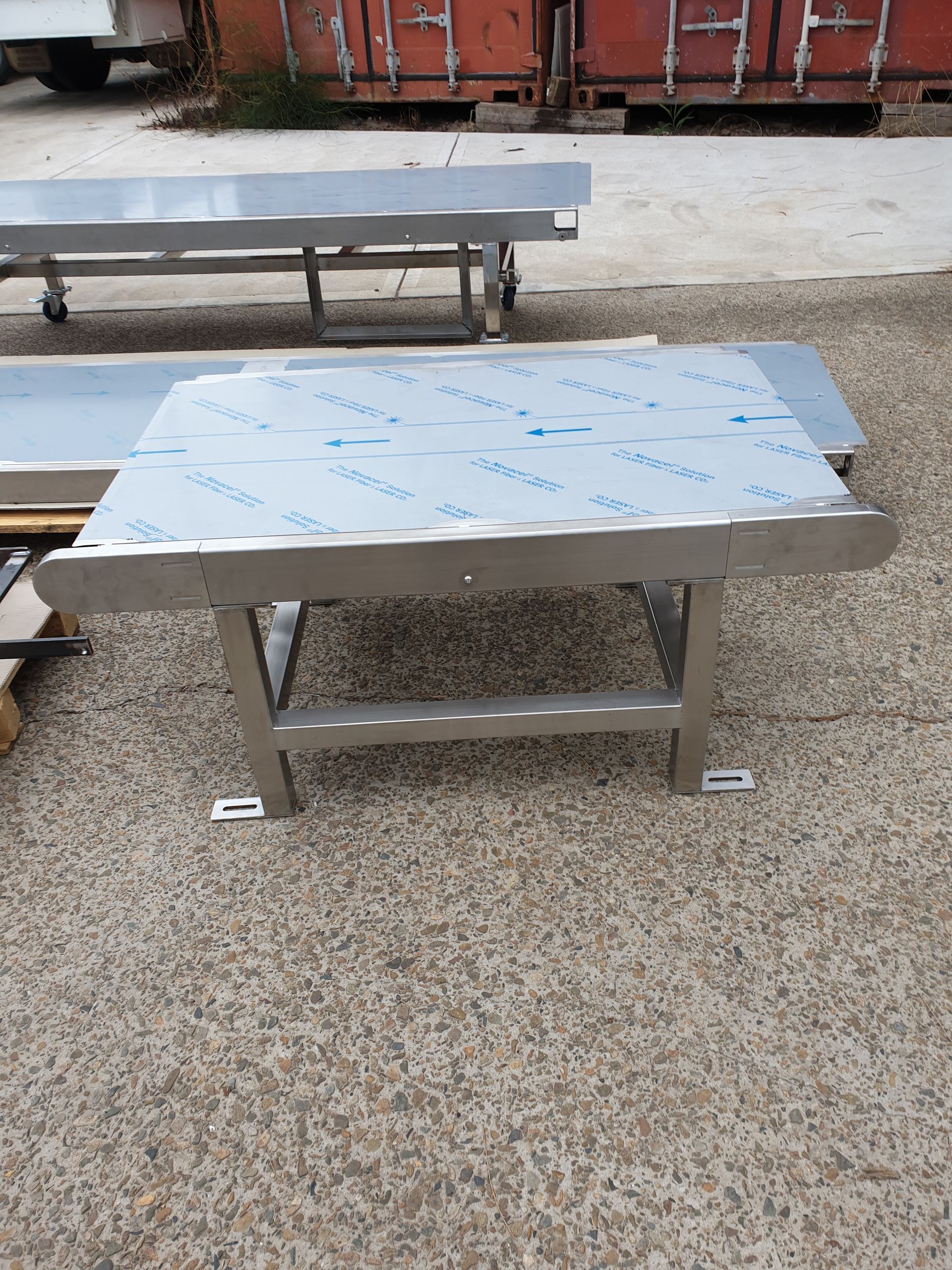 A stainless steel table is sitting on the ground in a parking lot.