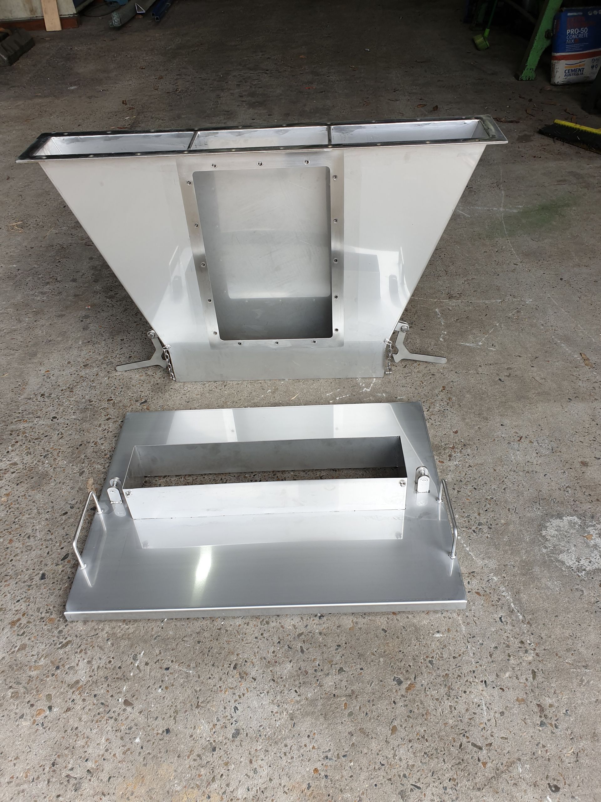 A stainless steel container is sitting on a concrete surface.