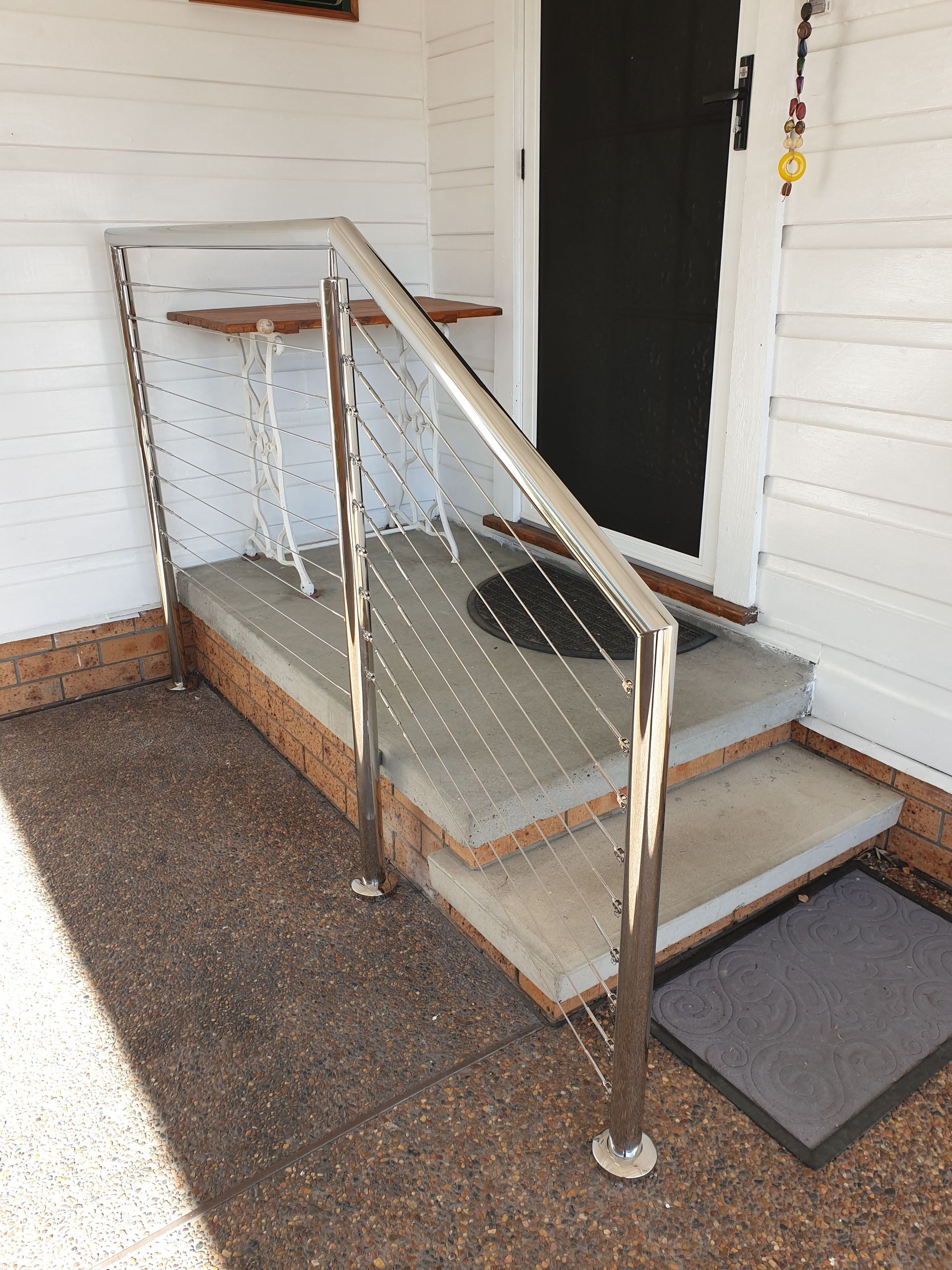 A staircase with a stainless steel railing and steps leading up to a door.