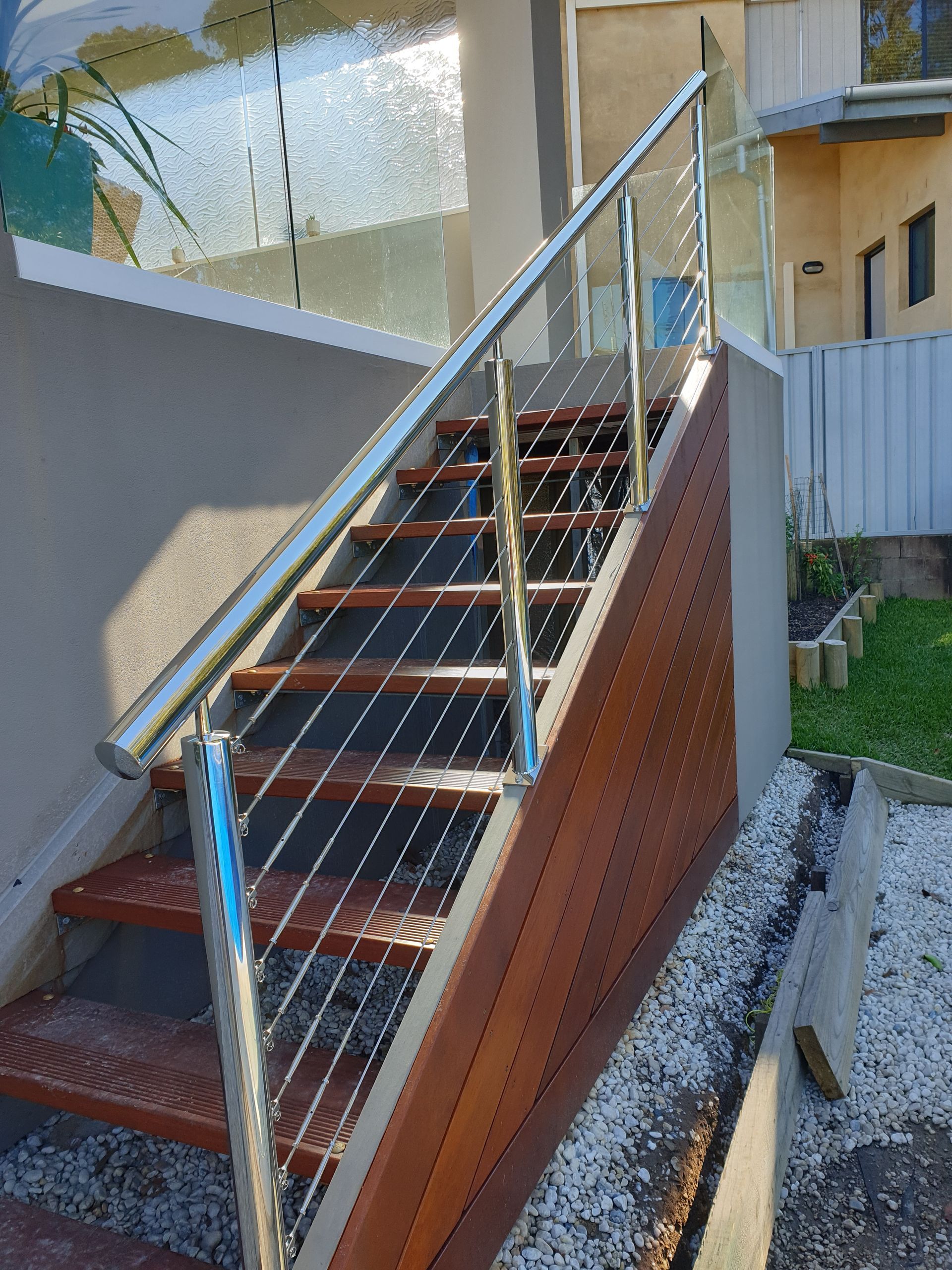 A set of wooden stairs with a stainless steel railing