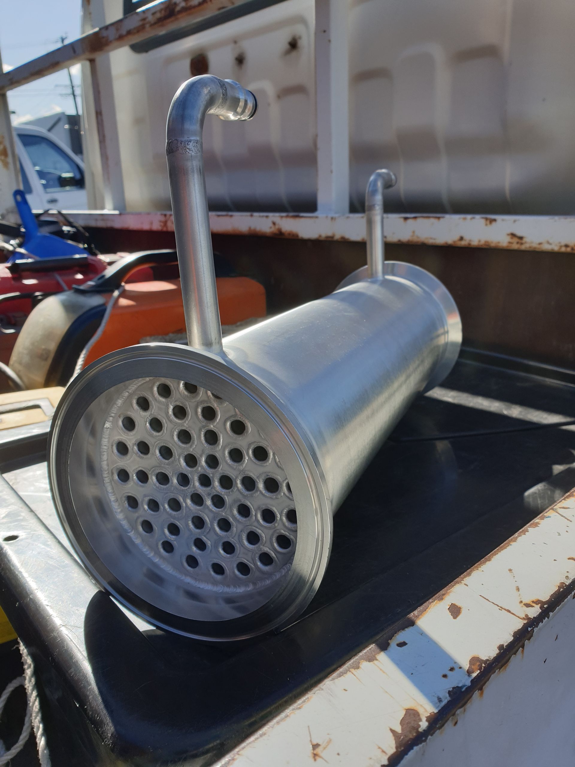 A metal pipe with holes in it is sitting on top of a black table.