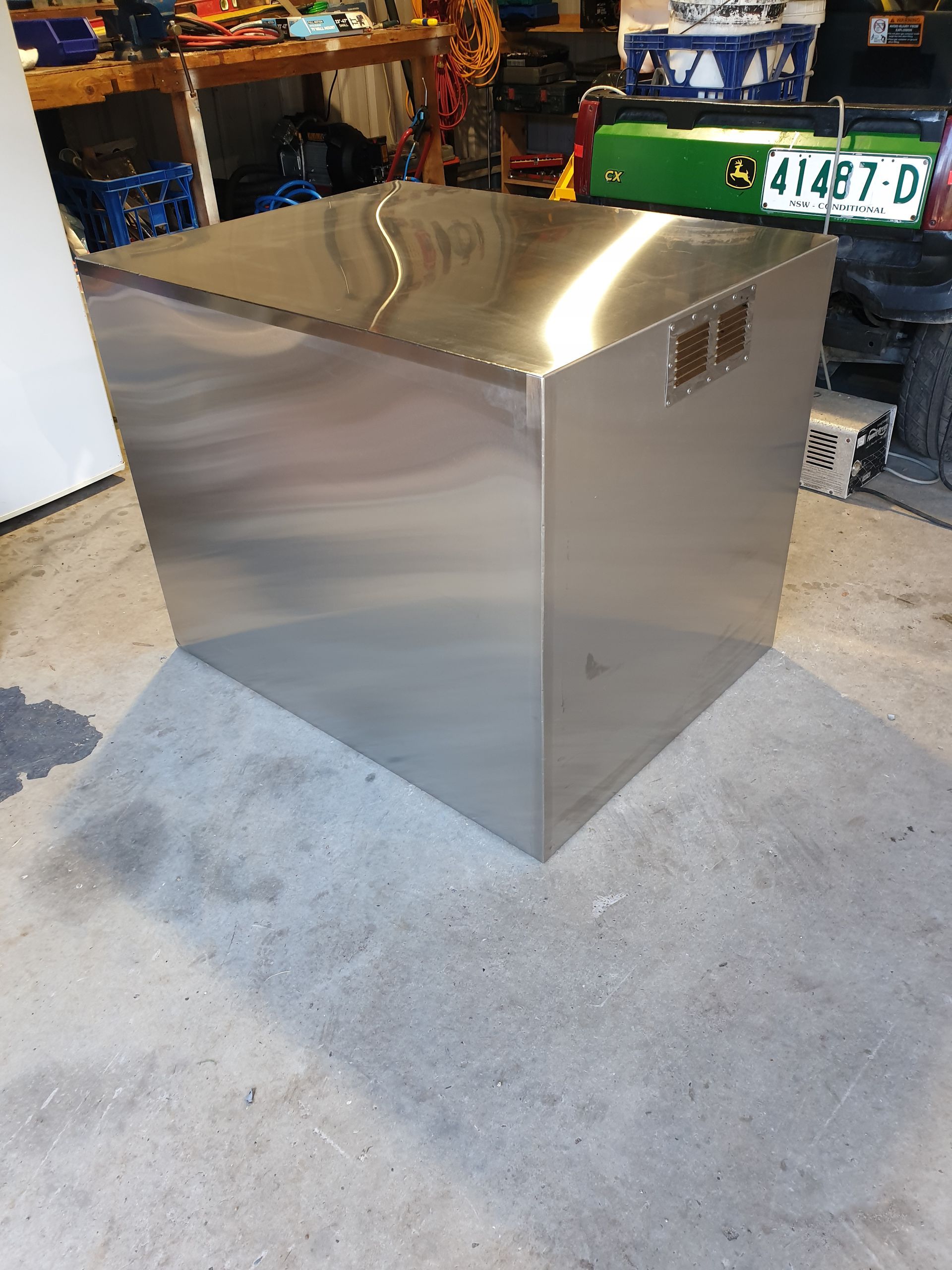 A large stainless steel box is sitting on the floor in a garage.