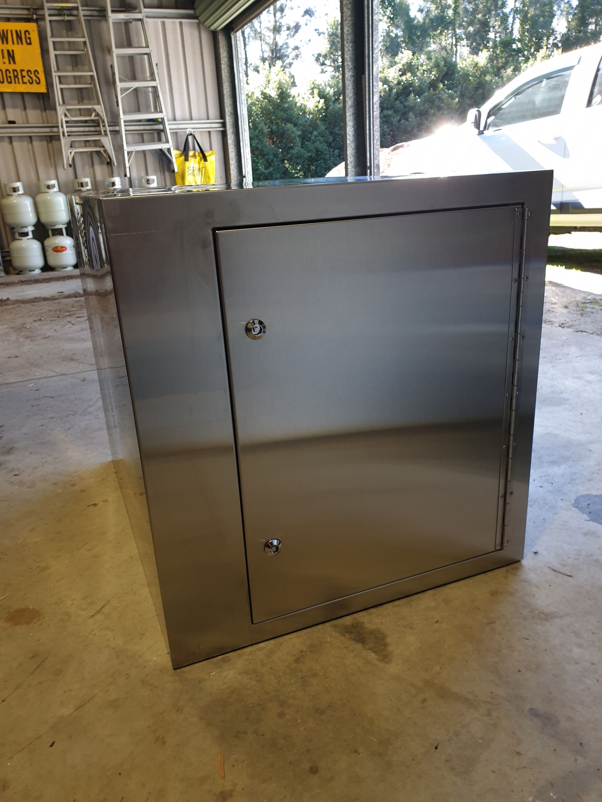 A stainless steel box is sitting on the floor in a garage.