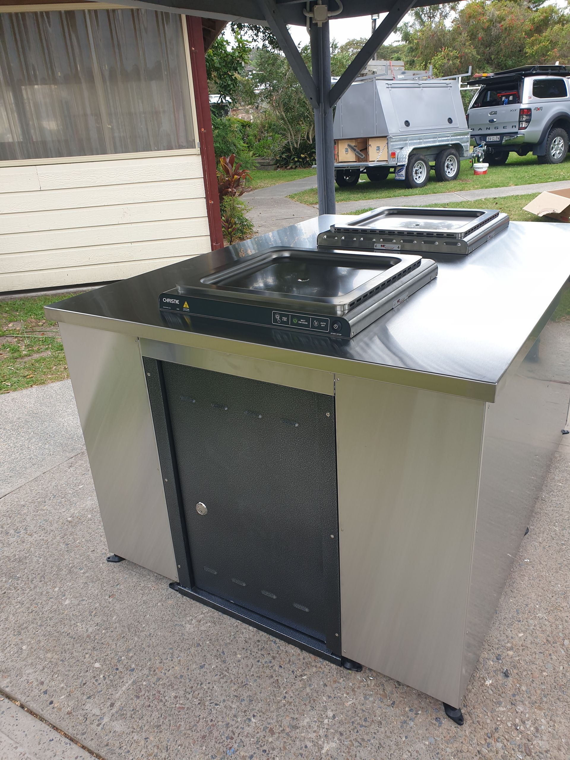 A stainless steel table with a black door is sitting on a sidewalk.