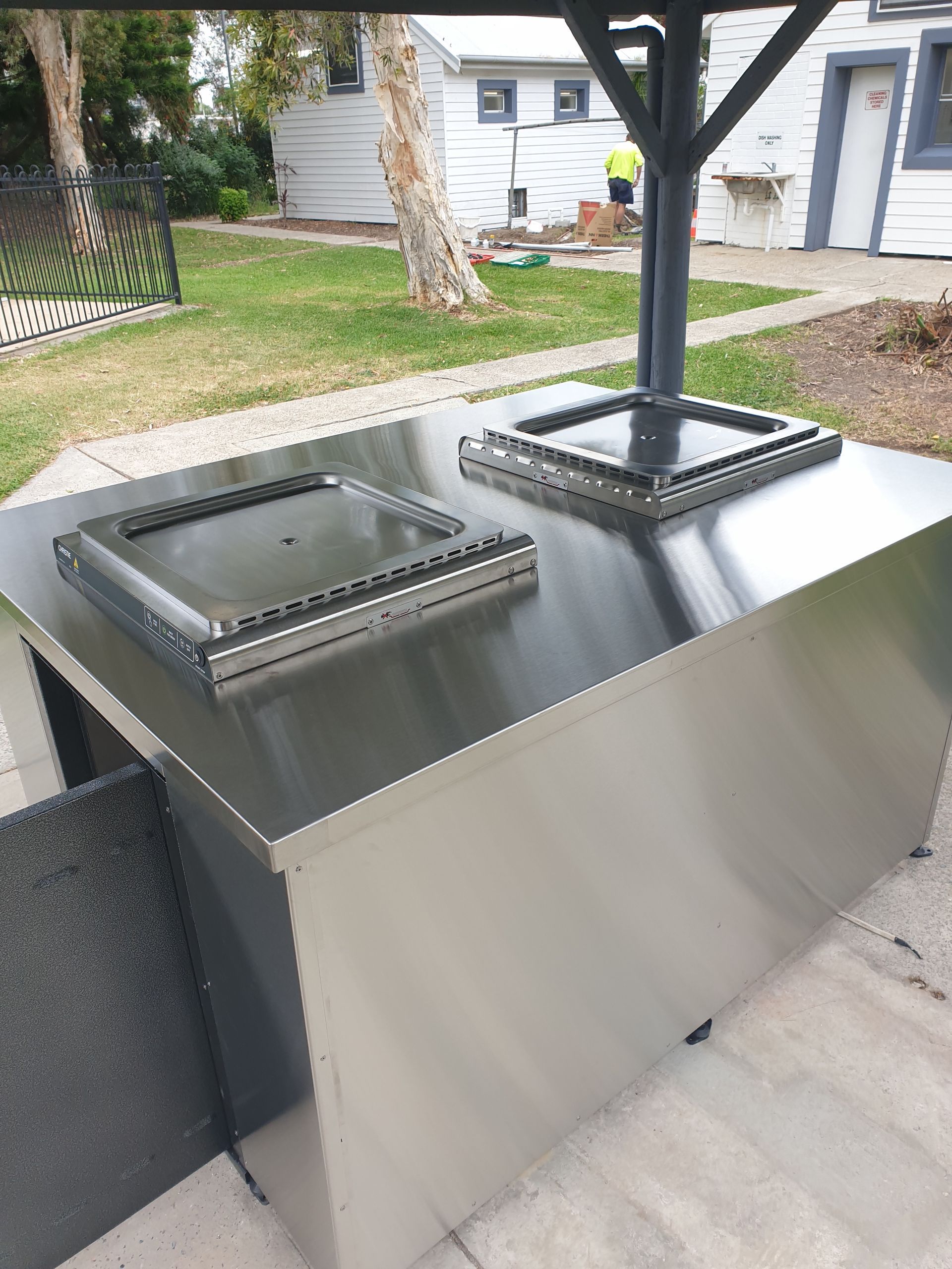 A stainless steel table is sitting on a patio next to a house.