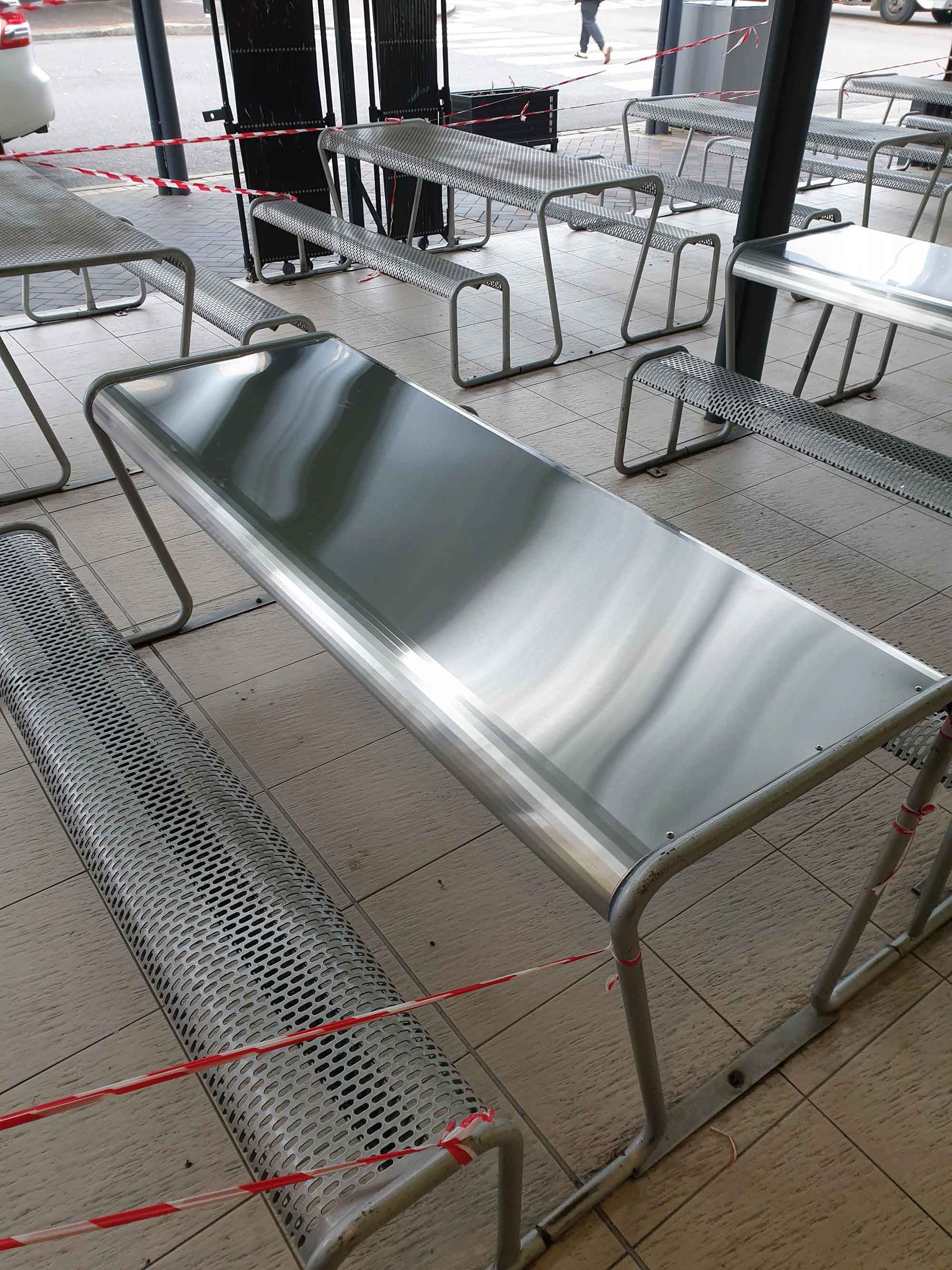 A stainless steel bench is sitting on a tiled floor
