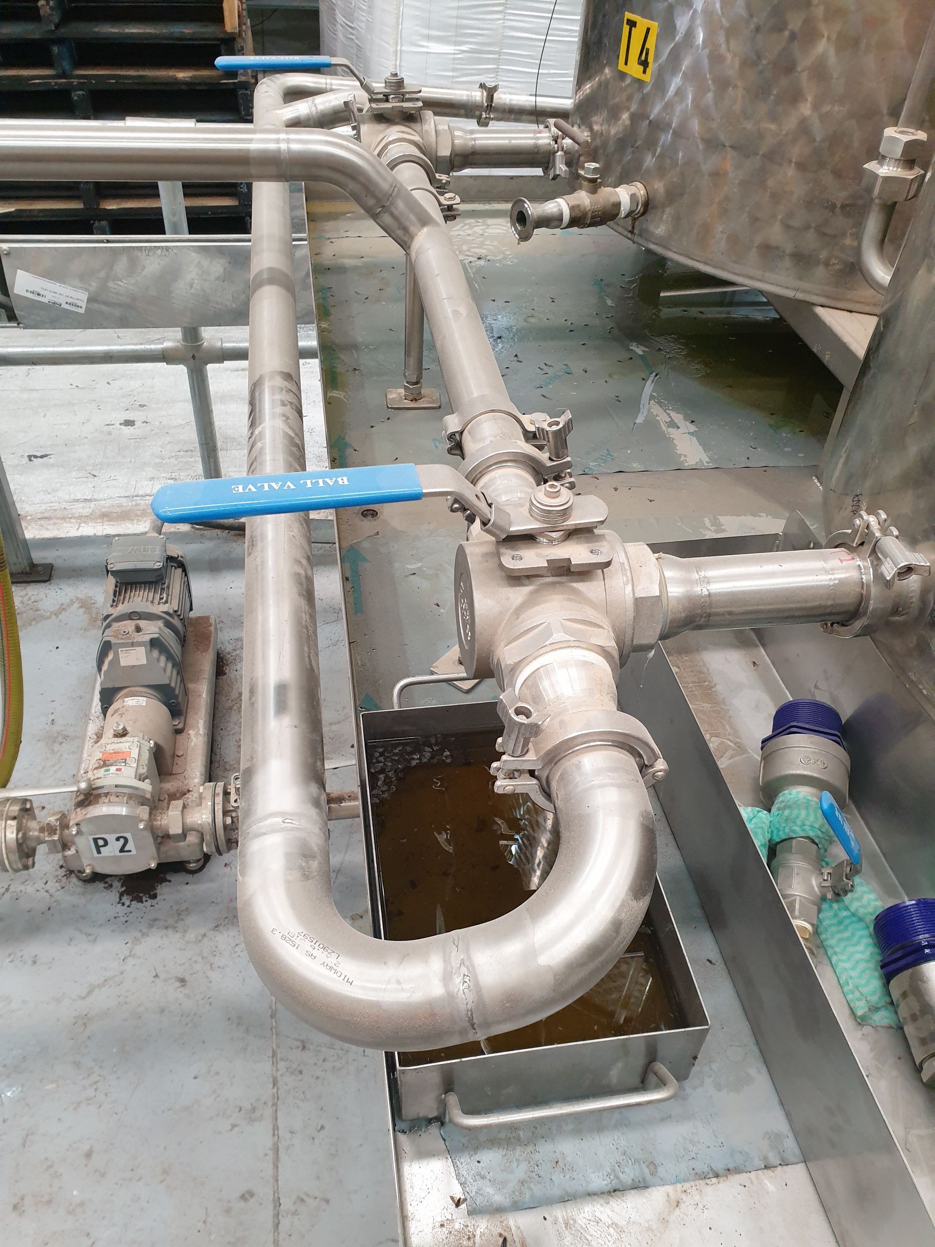 A stainless steel pipe with a blue valve is connected to a tank.