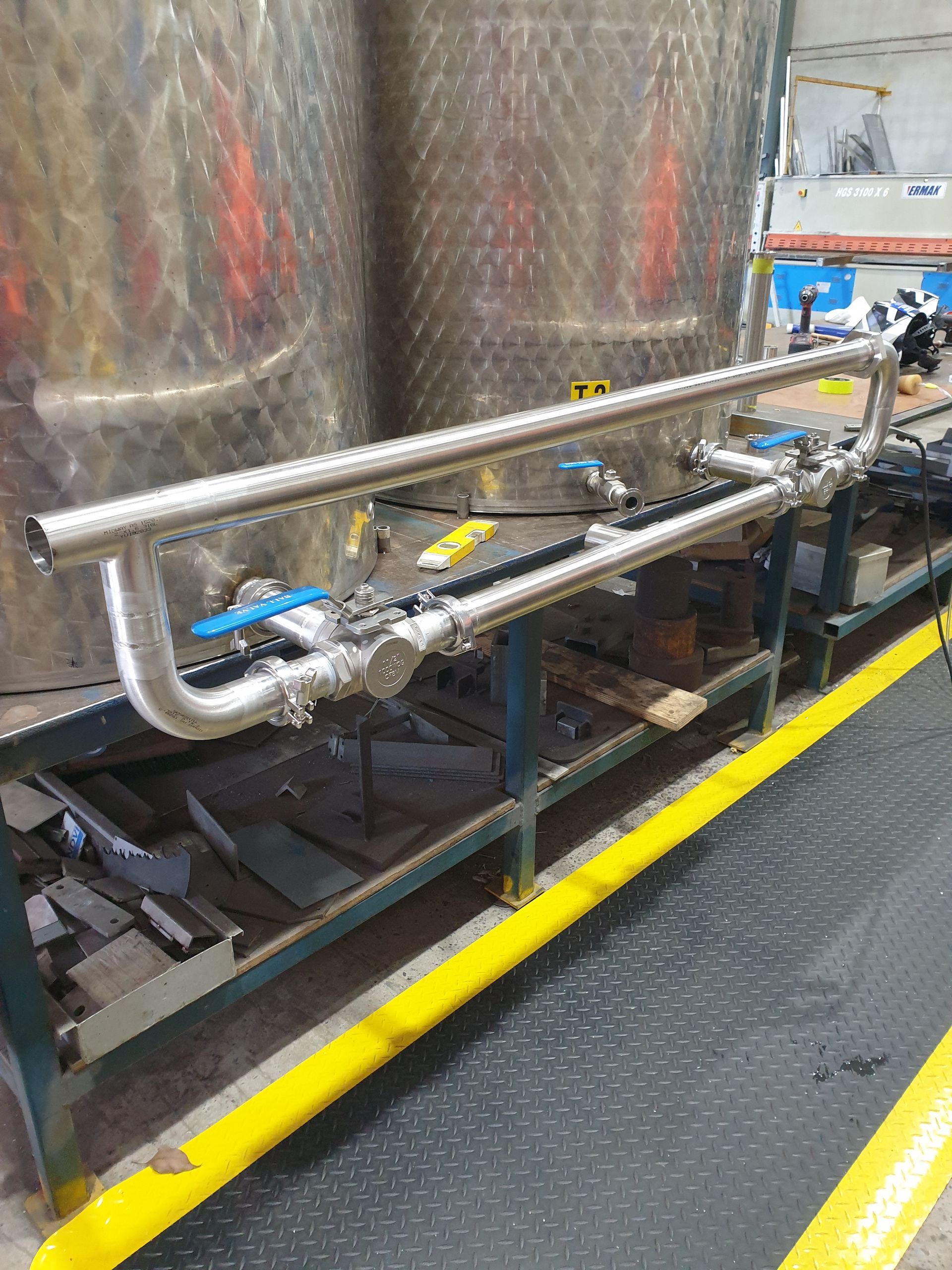 A stainless steel pipe is sitting on a table in a factory.