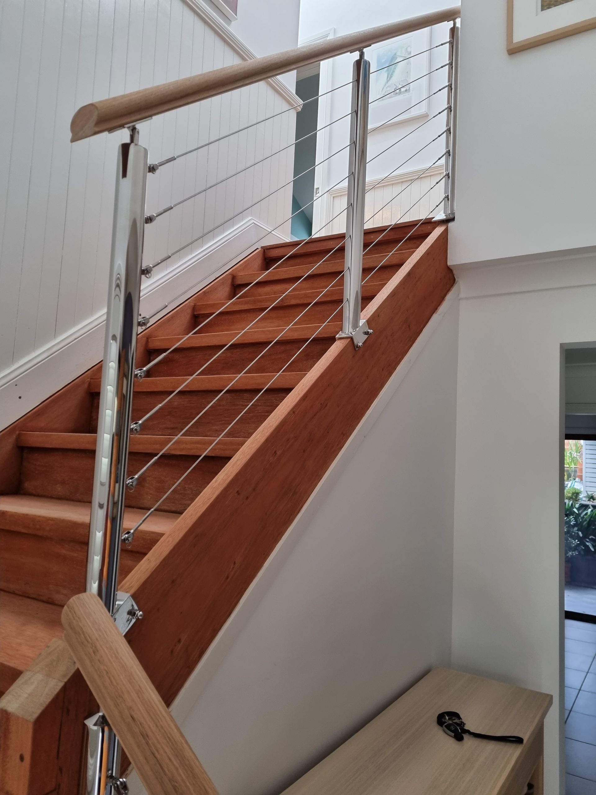 A wooden staircase with a stainless steel railing