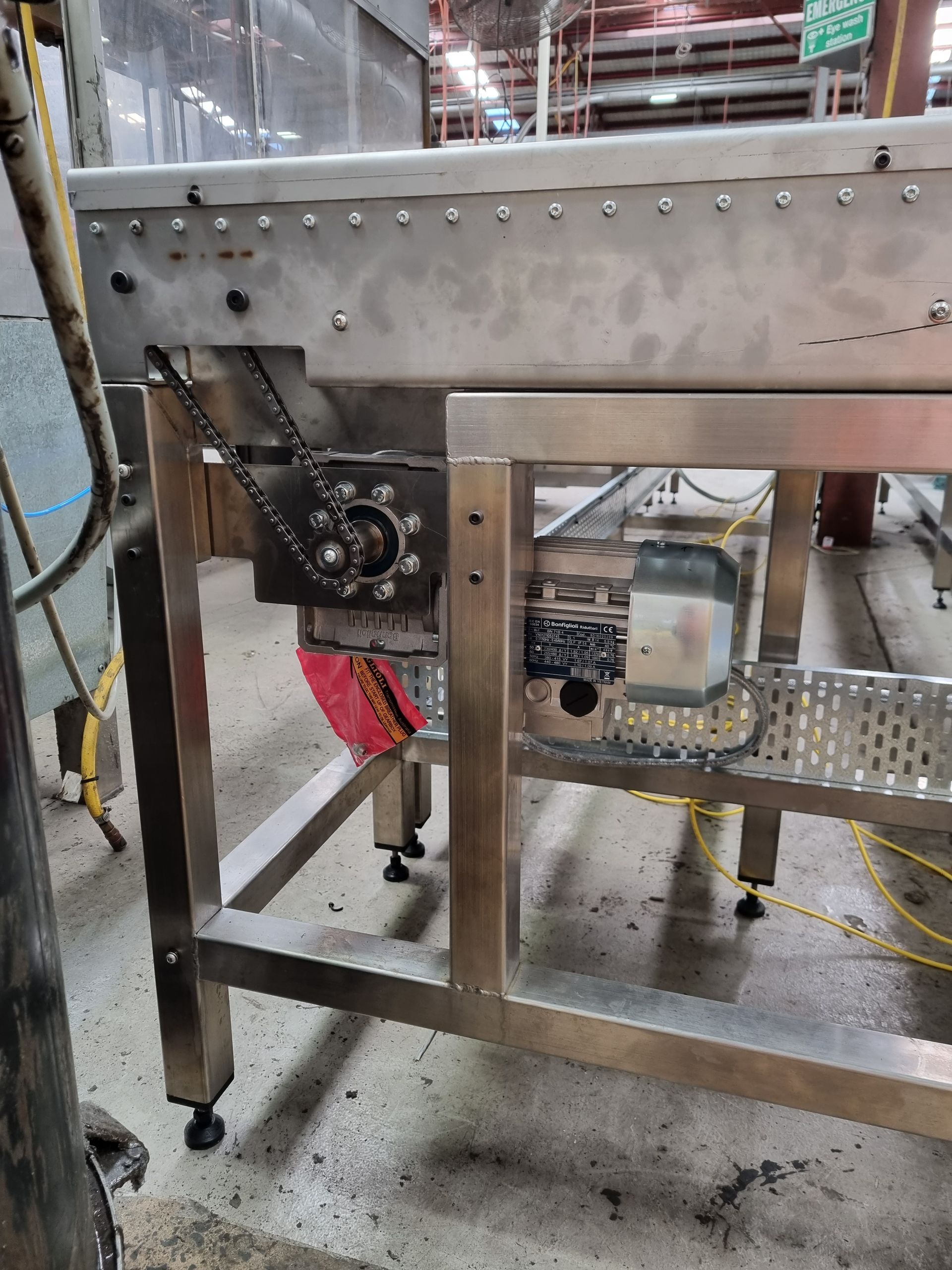 A stainless steel conveyor belt is sitting on the floor in a factory.