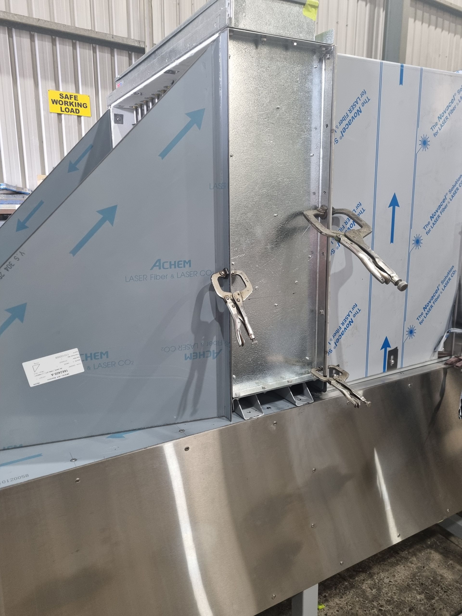 A stainless steel machine with two keys on it is sitting in a warehouse.