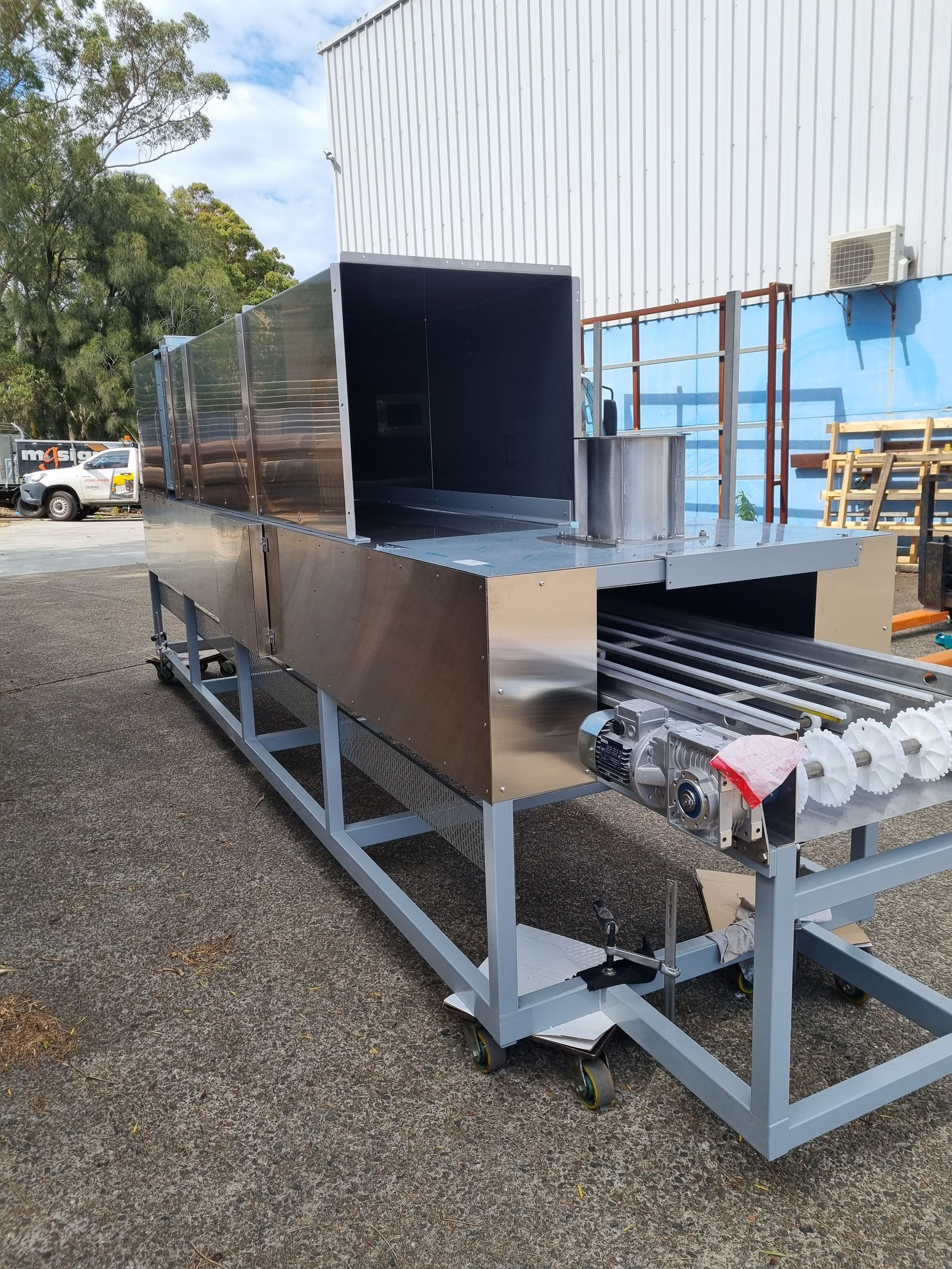 A large stainless steel machine is sitting in front of a building.