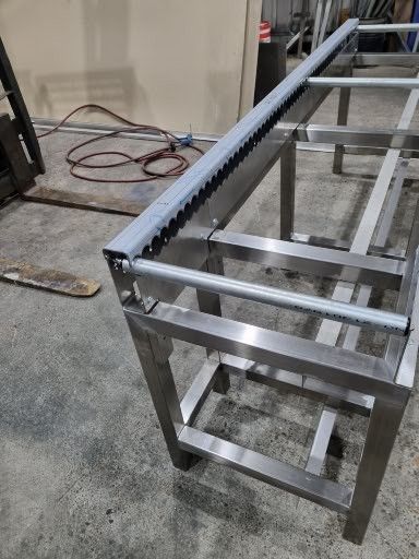 A stainless steel table with a conveyor belt attached to it.