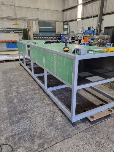 A large metal table is being built in a factory.