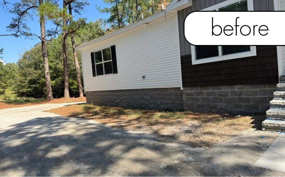 Before photo of a white house exterior with black shutters and stone foundation, shown from the driveway