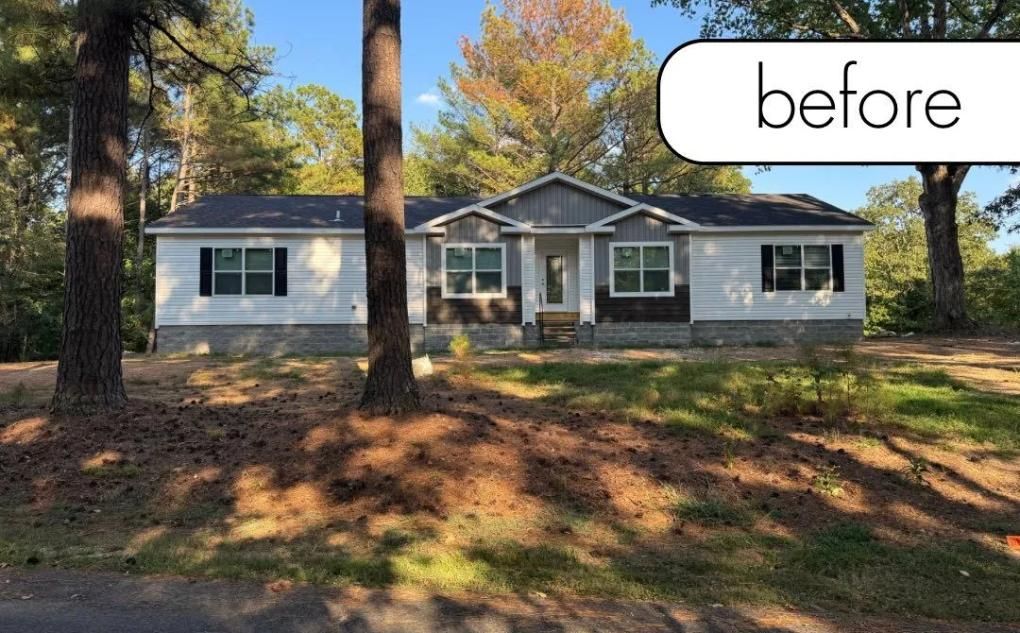 Before photo of a single-story gray house with white trim and a front porch, surrounded by trees