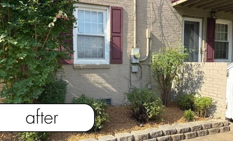 Front of brick house with windows, maroon shutters, and a landscaped garden bed labeled 