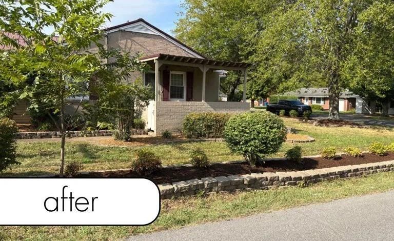Front yard of a house with trimmed shrubs, trees, and a mulch border along the street.