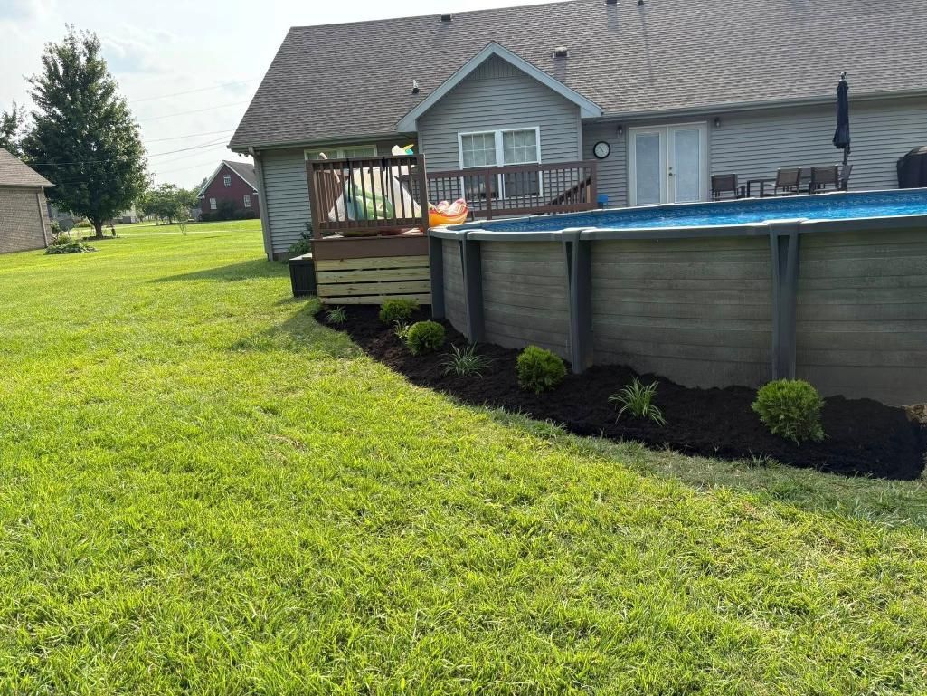 Backyard with above-ground pool, wooden deck, and house beside a grassy lawn