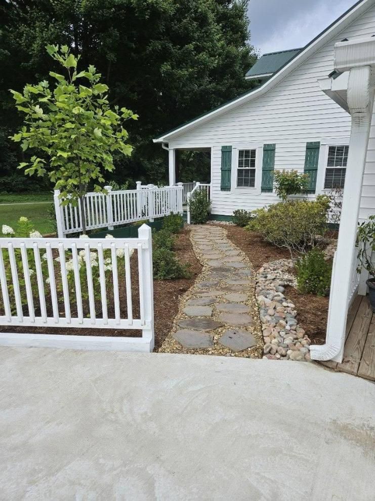 White picket-fenced garden path with stone walkway leading to a white house entrance