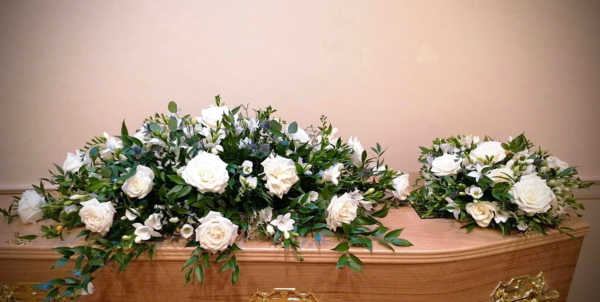 A wooden coffin decorated with white flowers and greenery.