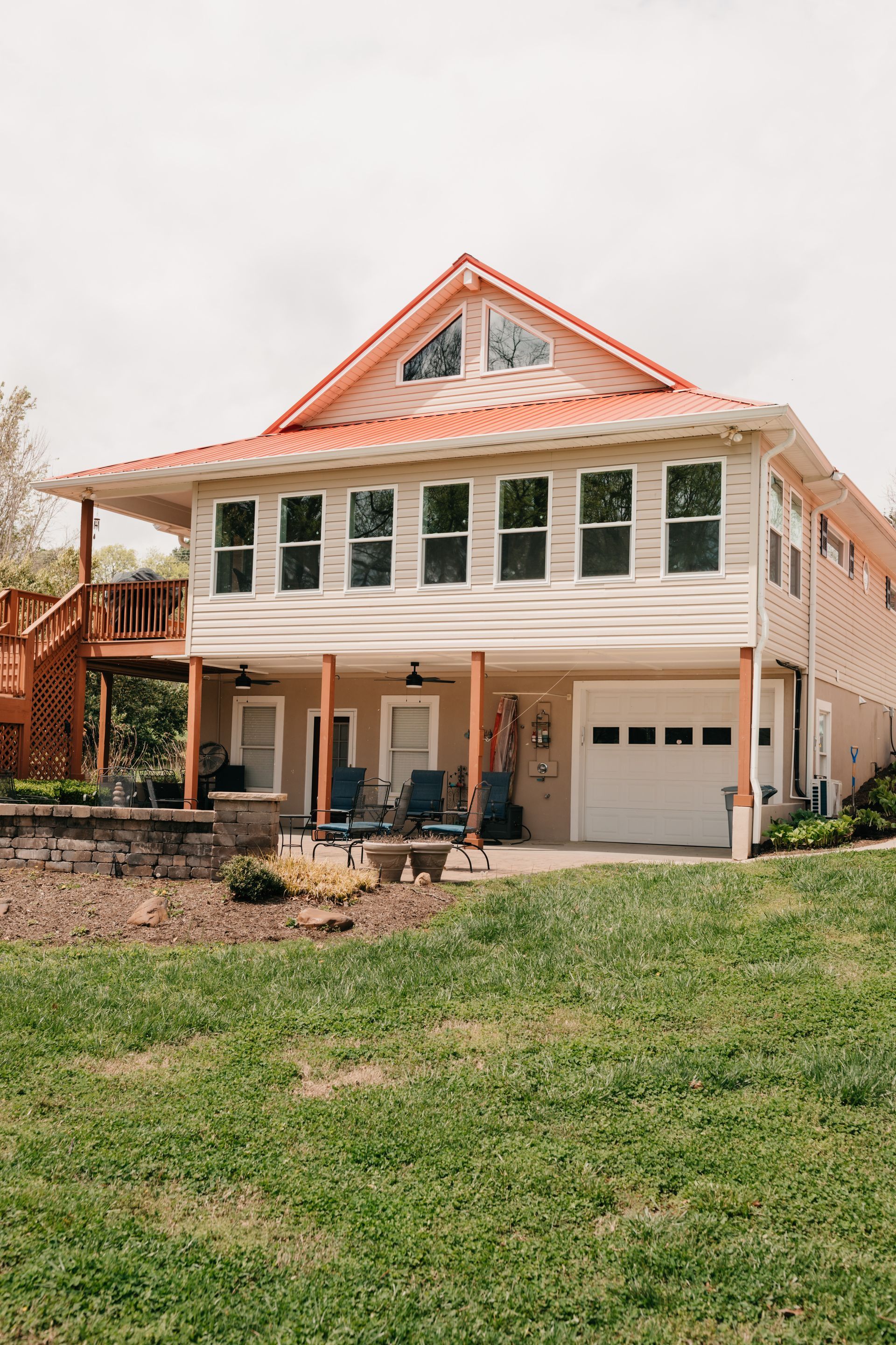 A large white house with a red roof is sitting on top of a grassy hill.