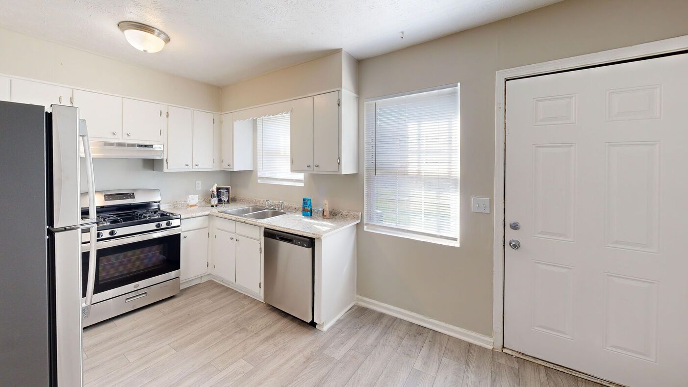 Kitchen with white cabinets, stainless steel appliances, and a gray floor.