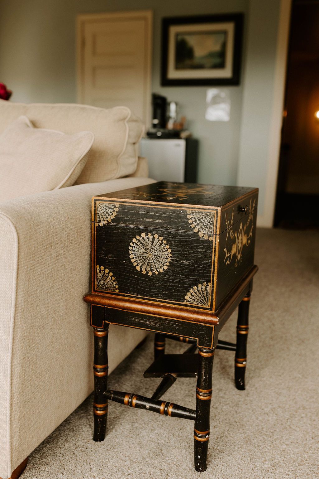 Small black-and-gold decorative table beside a beige sofa in a living room