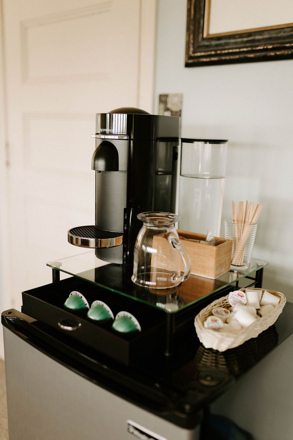 Coffee and tea station with a black machine, cups, kettle, and supplies on a countertop