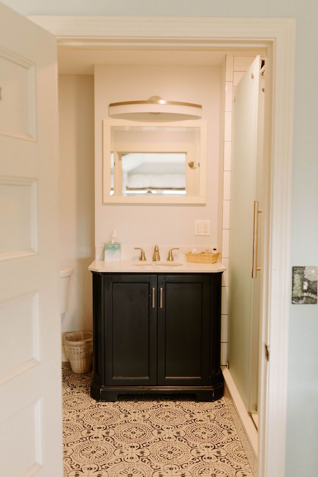 Small bathroom vanity with dark cabinet, mirror, and beige walls in a narrow hallway.