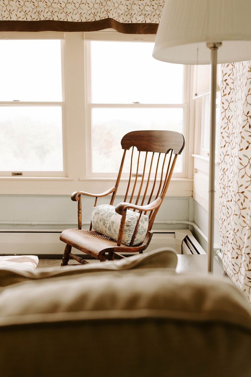 Wooden rocking chair by bright windows in a cozy living room