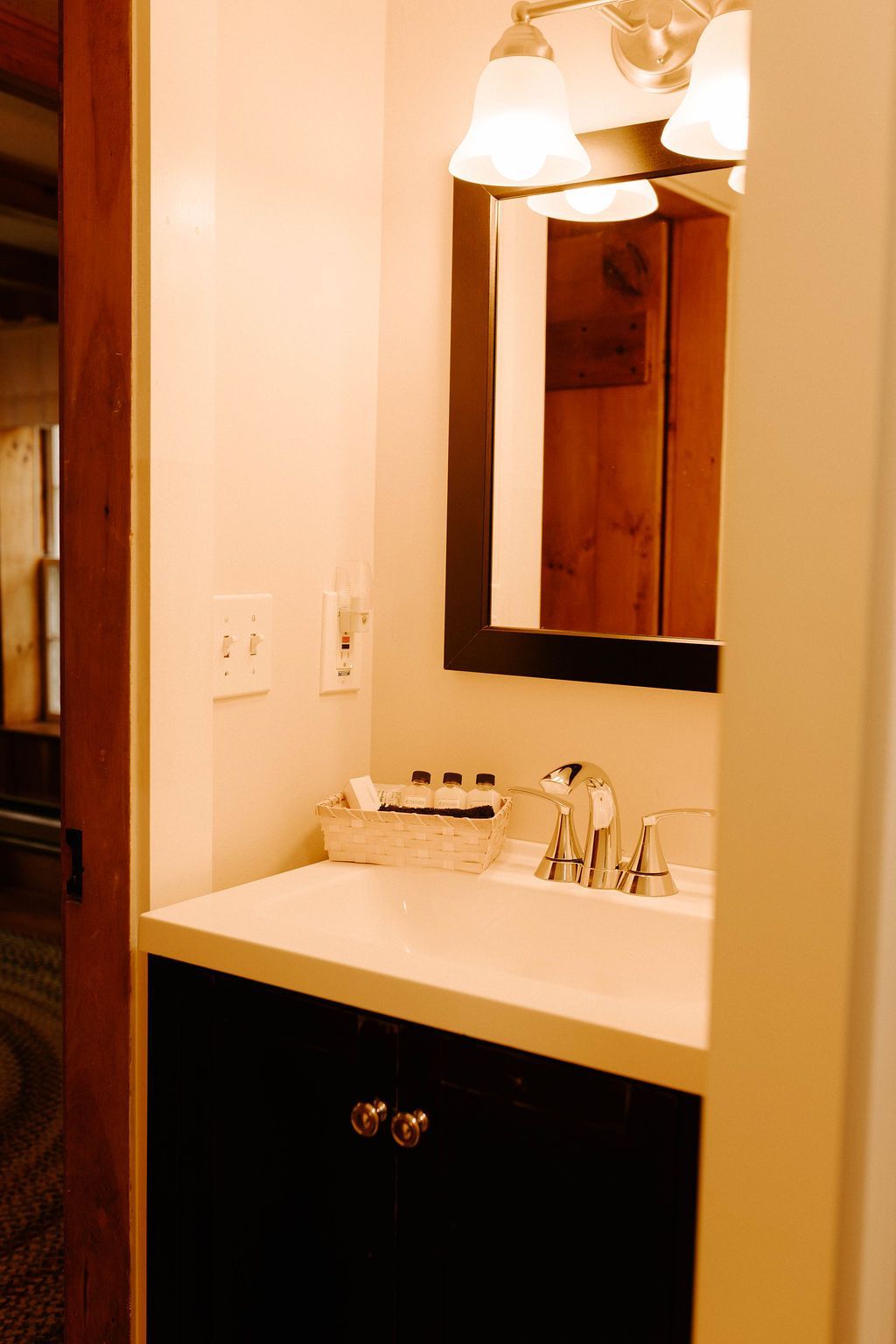 Bathroom vanity with mirror, sink, and light fixtures in a narrow beige alcove