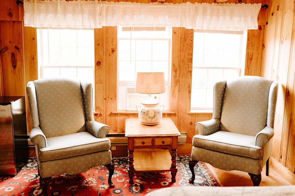 Cozy living room with two upholstered armchairs, a small wooden table, and warm wood-paneled walls