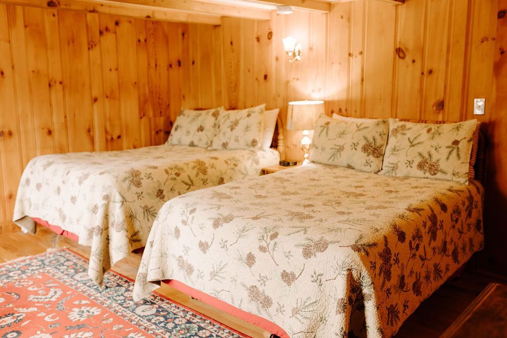 Two twin beds with floral bedspreads in a warm wood-paneled bedroom