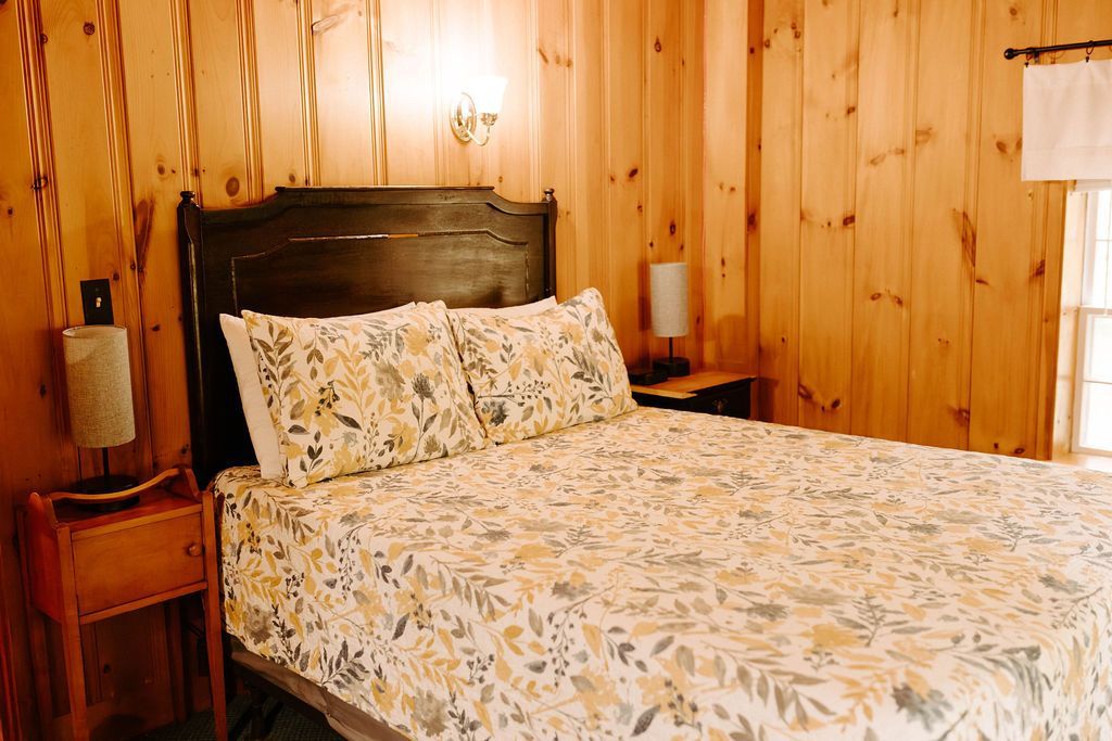 Cozy bedroom with wood-paneled walls, a dark headboard, and a bed with floral bedding