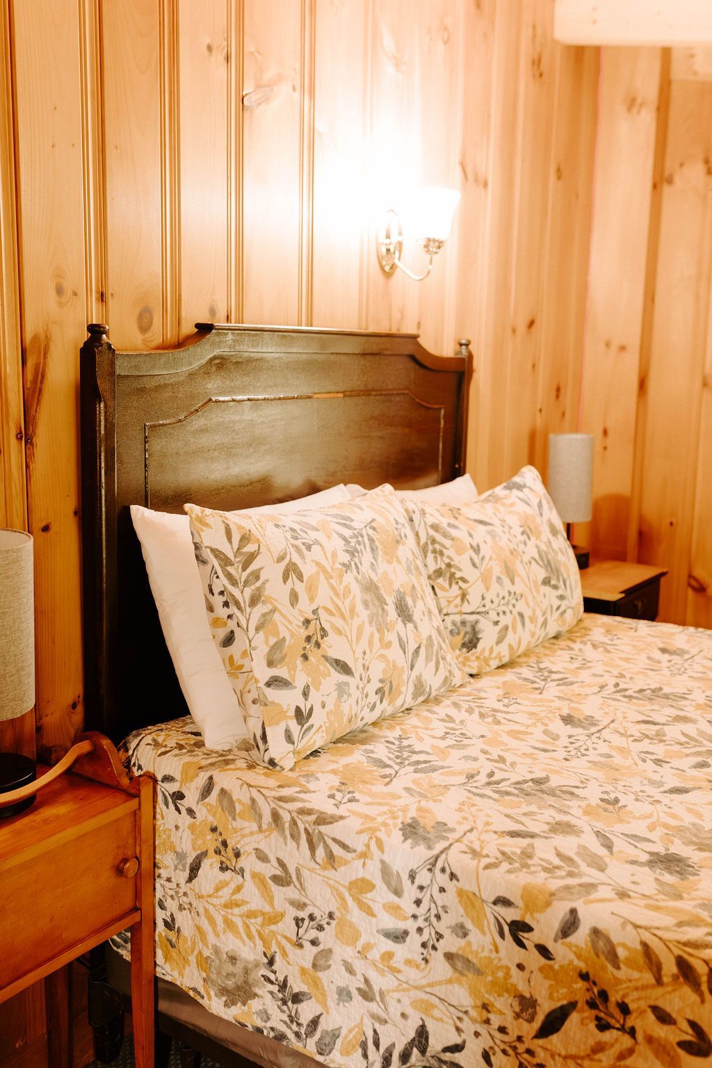 Wood-paneled bedroom with a bed, floral bedding, and a wooden headboard