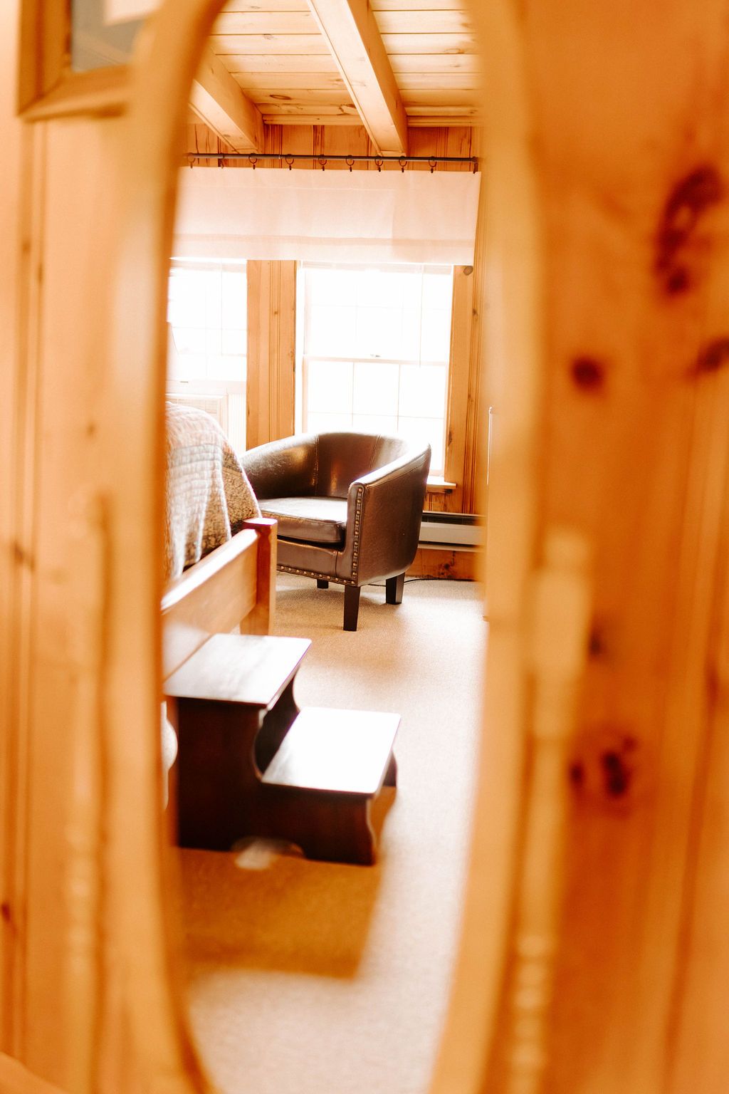 View through a wooden keyhole into a sunlit room with a chair and steps