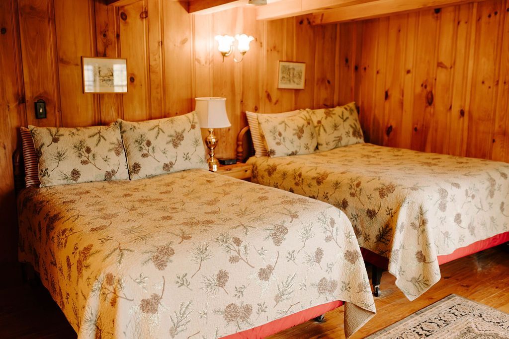 Two twin beds with floral bedspreads in a wood-paneled bedroom