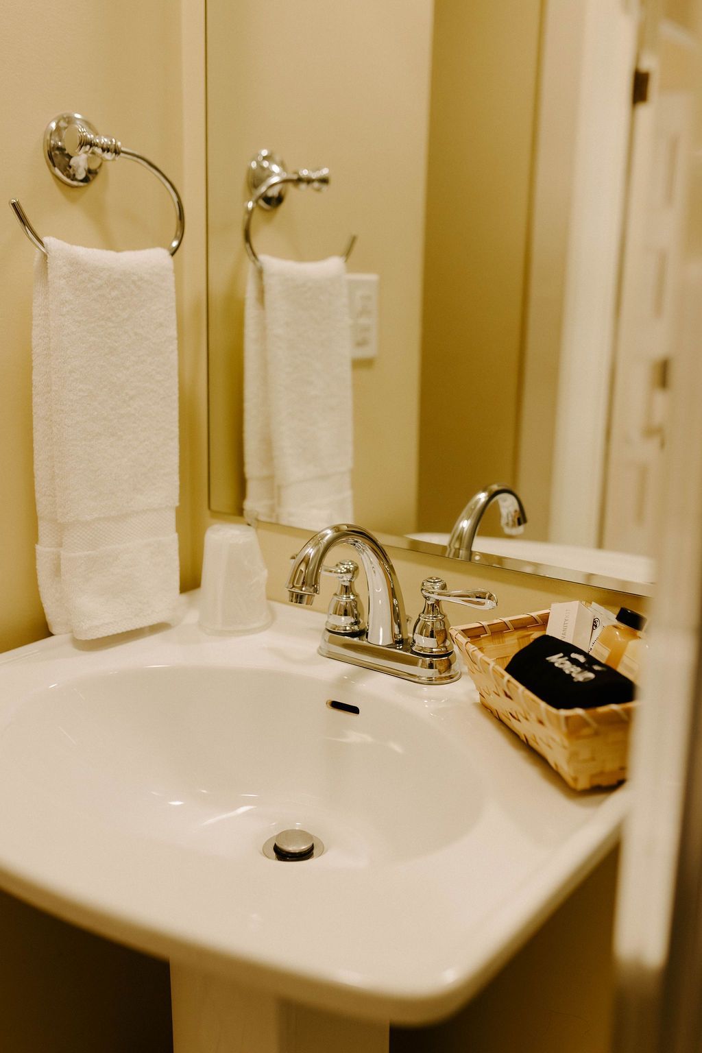 Bathroom sink with mirror, towel rack, and wicker basket on the counter.