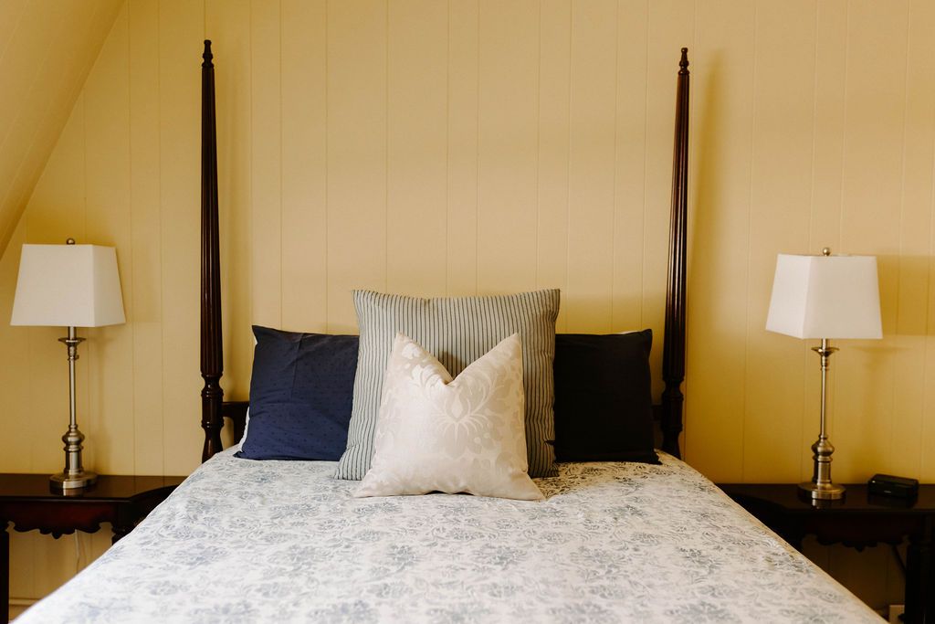 Symmetrical bedroom with a four-poster bed, white bedding, and matching bedside lamps