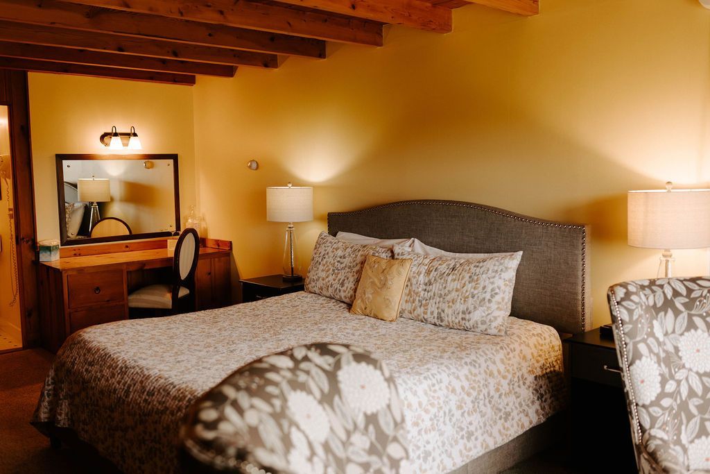 Cozy bedroom with a large bed, bedside lamps, and a wooden desk with mirror in warm lighting