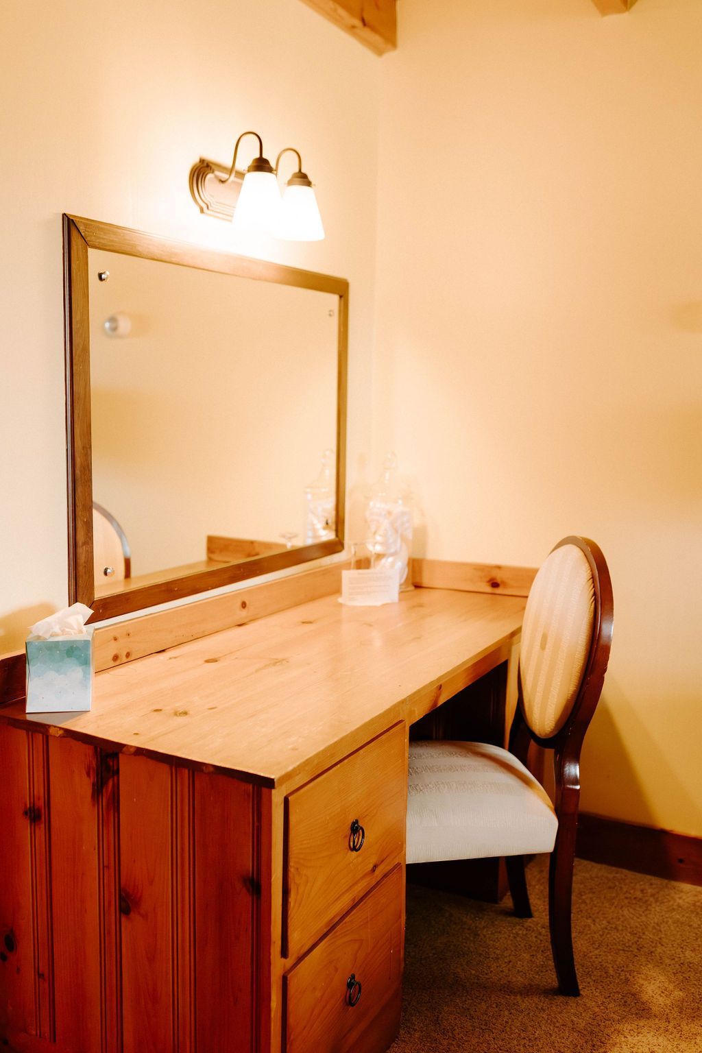 Wooden vanity table with mirror and chair in a softly lit room