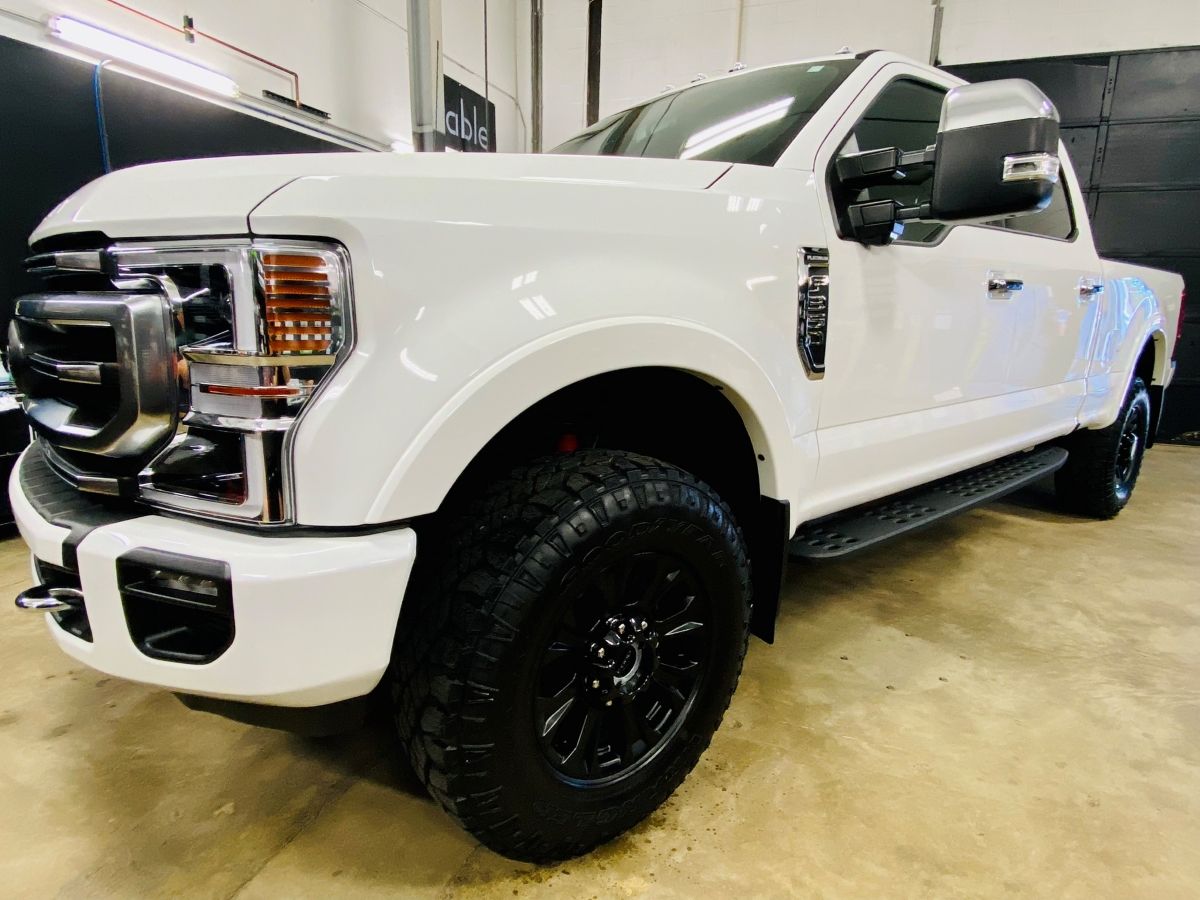 A white truck with black wheels is parked in a garage.