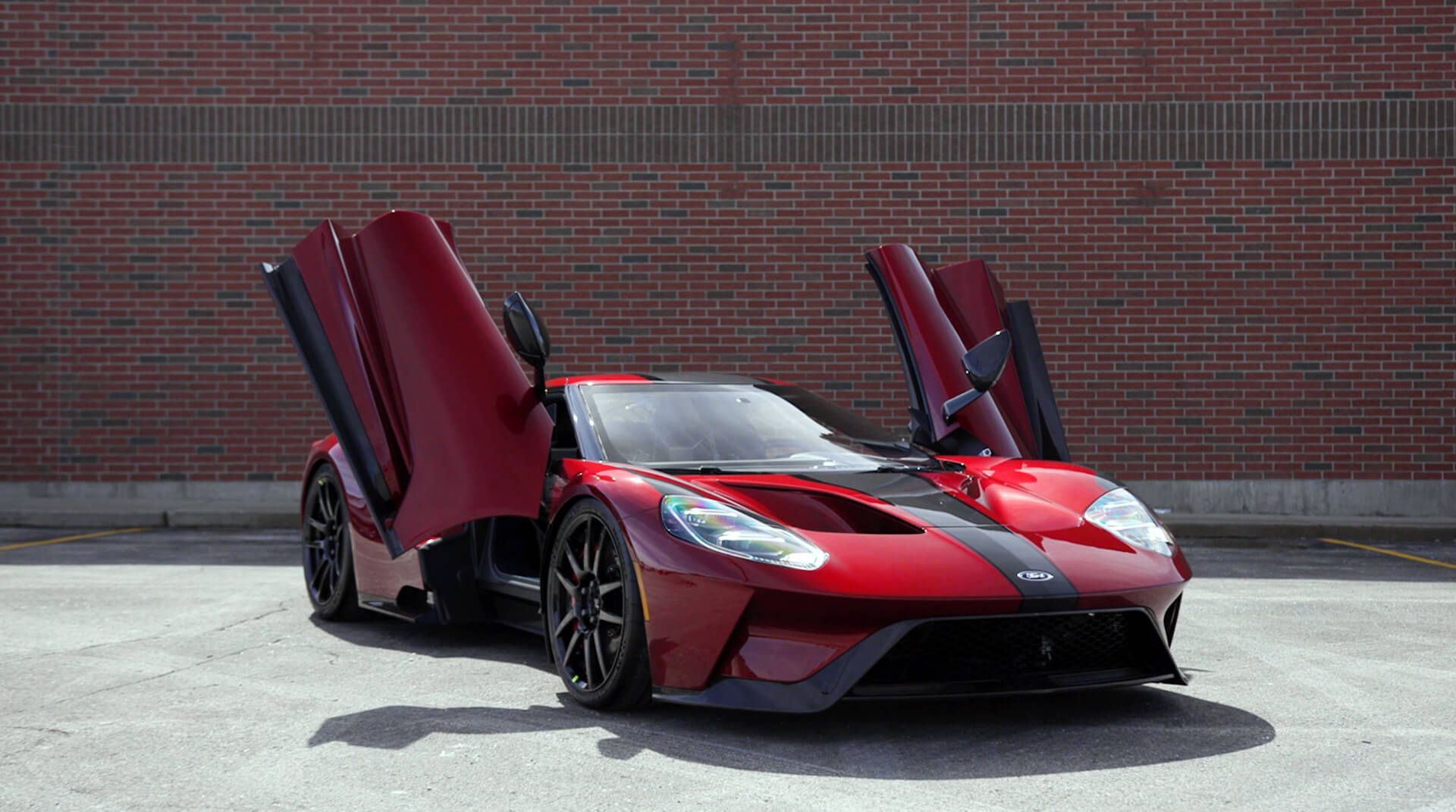 a red sports car with its doors open is parked in front of a brick building .
