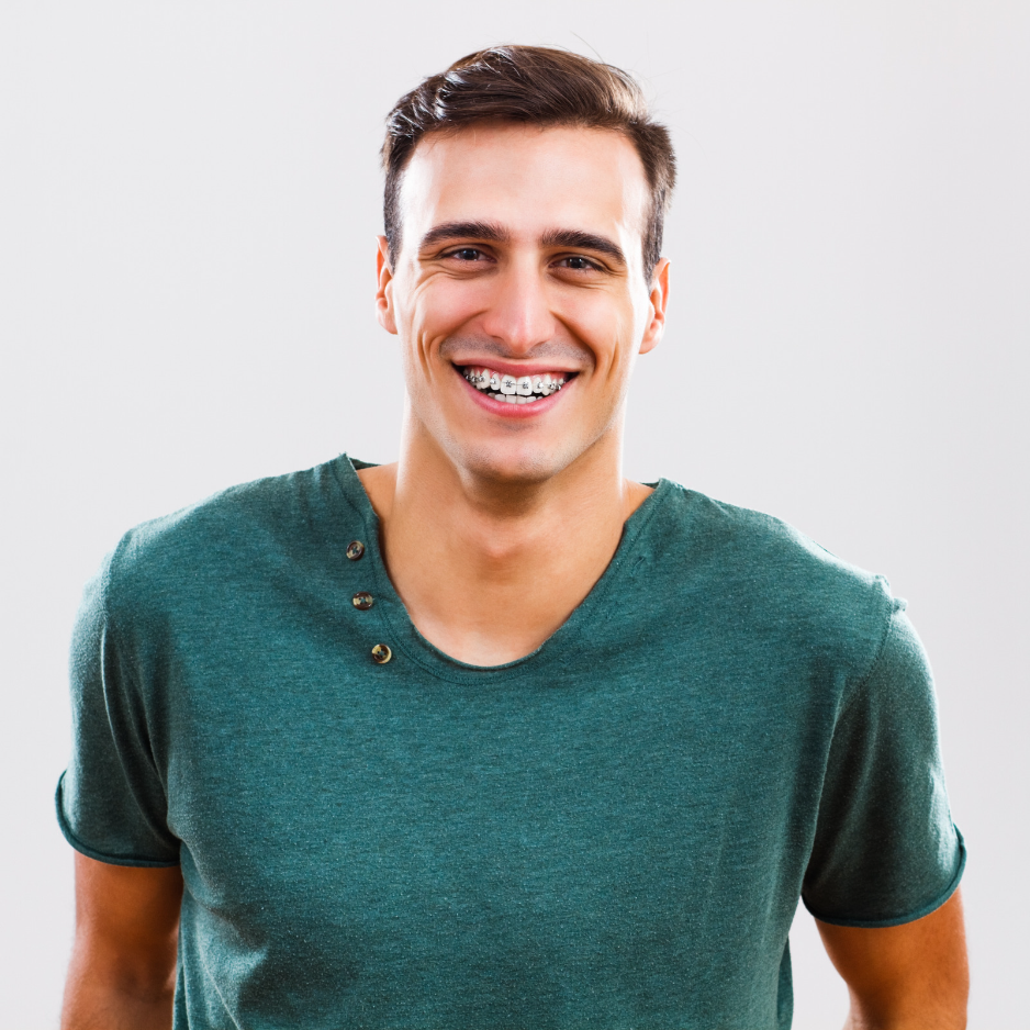 A man wearing braces and a green shirt is smiling.