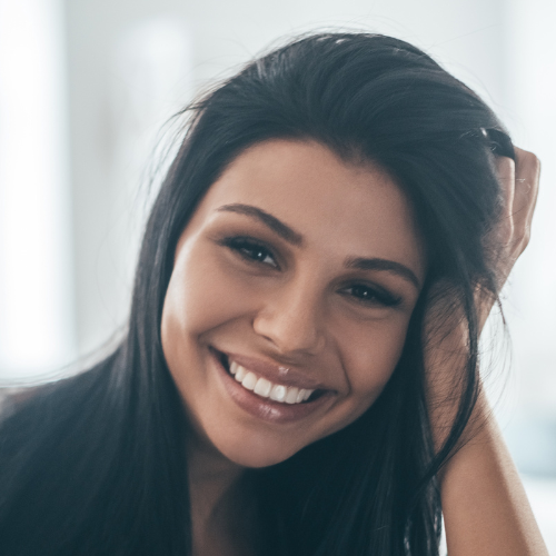 A woman is smiling with her hand in her hair.